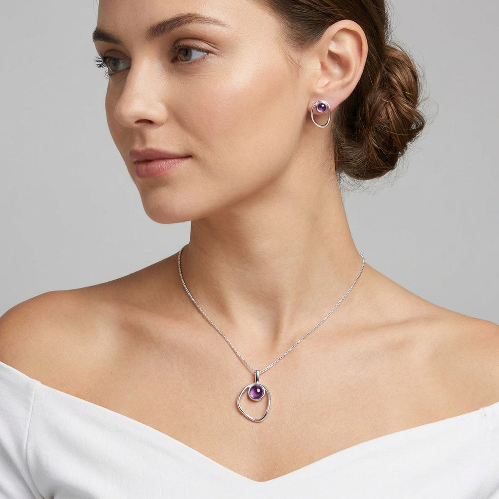 Woman wearing a Amethyst Birthstone Necklace - Sterling Silver and matching earrings on a gray background. Purplee Store