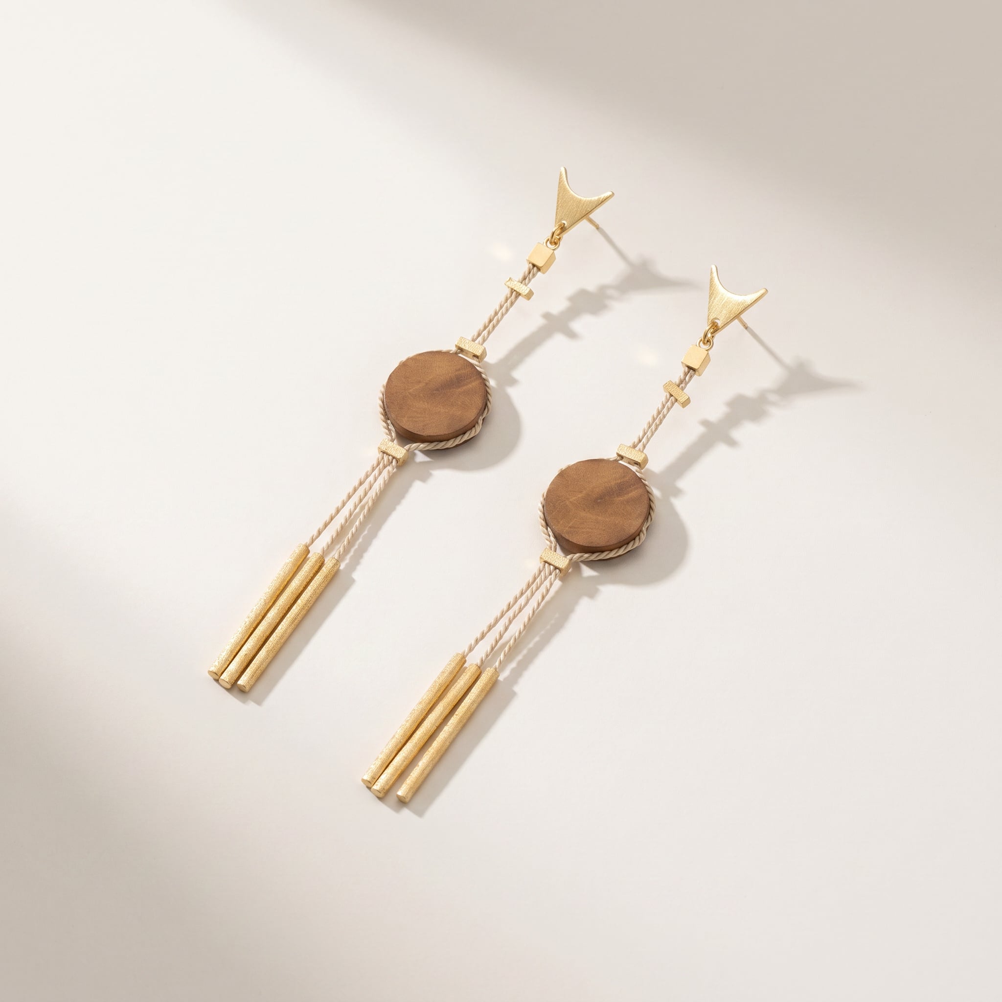 Pair of Purplee Store Buriti Amira Earrings with wooden discs and tassel details on a light background