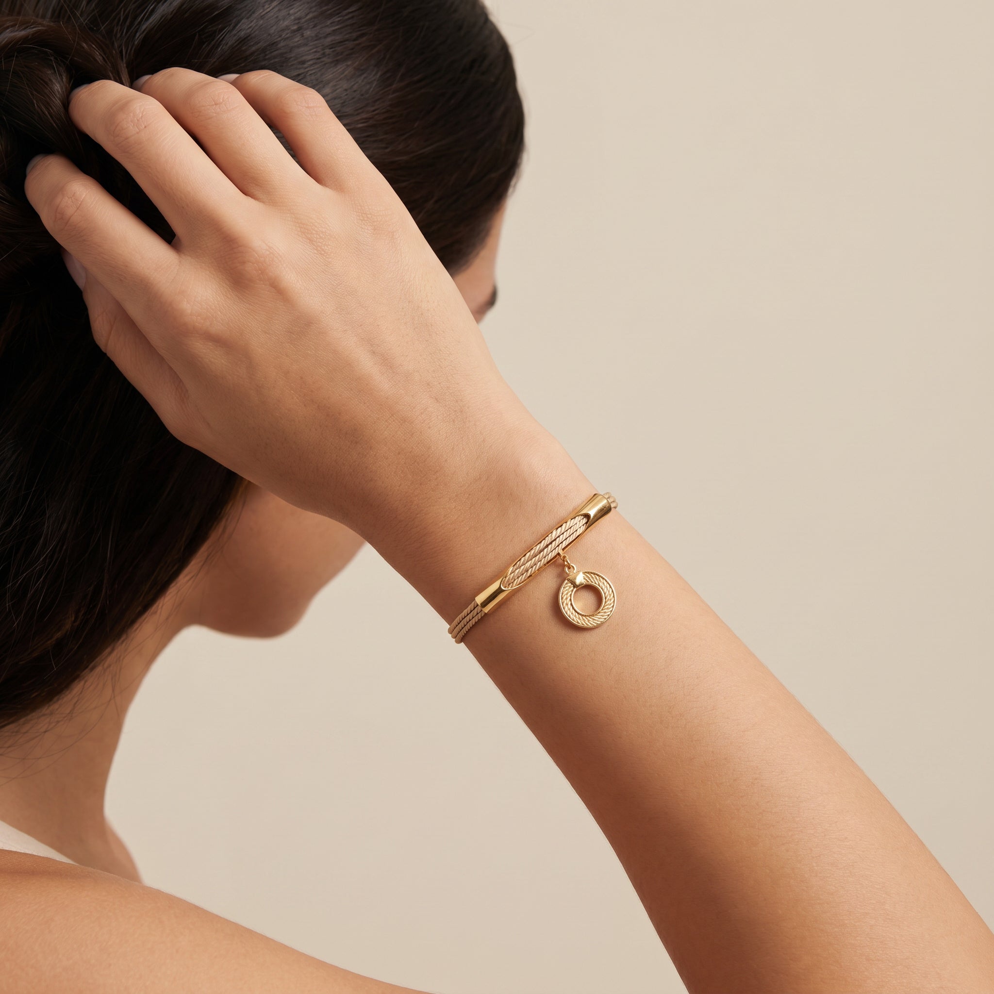 Purplee Store Gold bracelet with a circular charm on a person's wrist against a neutral background