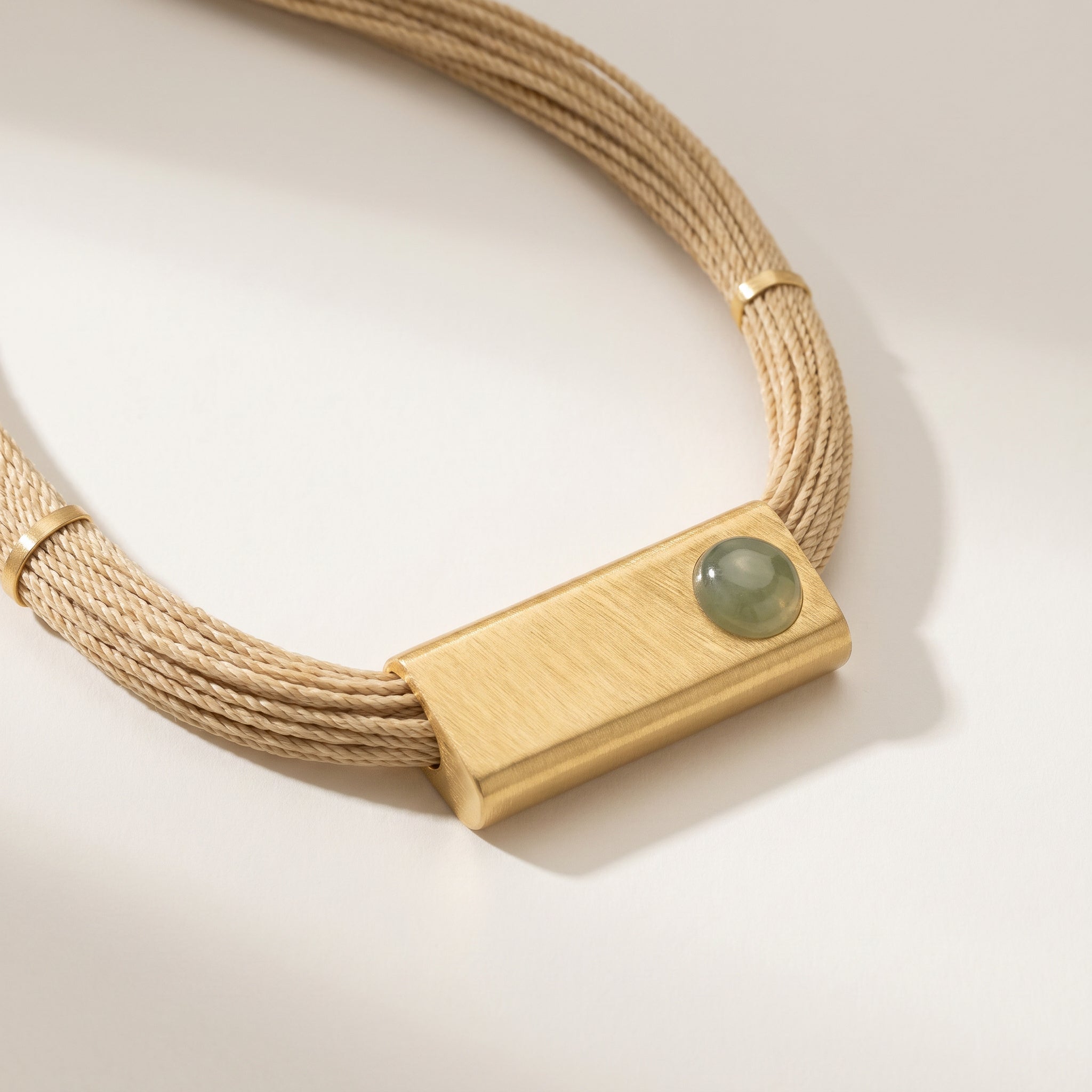 Purplee Store Buriti Geometric Orvellia Necklace with a rectangular gold clasp and green stone on a light background
