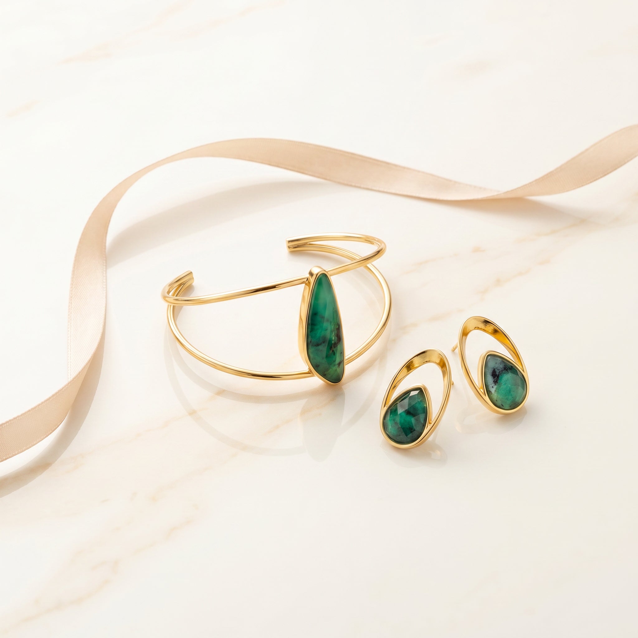 Purplee Store ELAN Emerald Sculptural Cuff and earrings with green stones on a white background