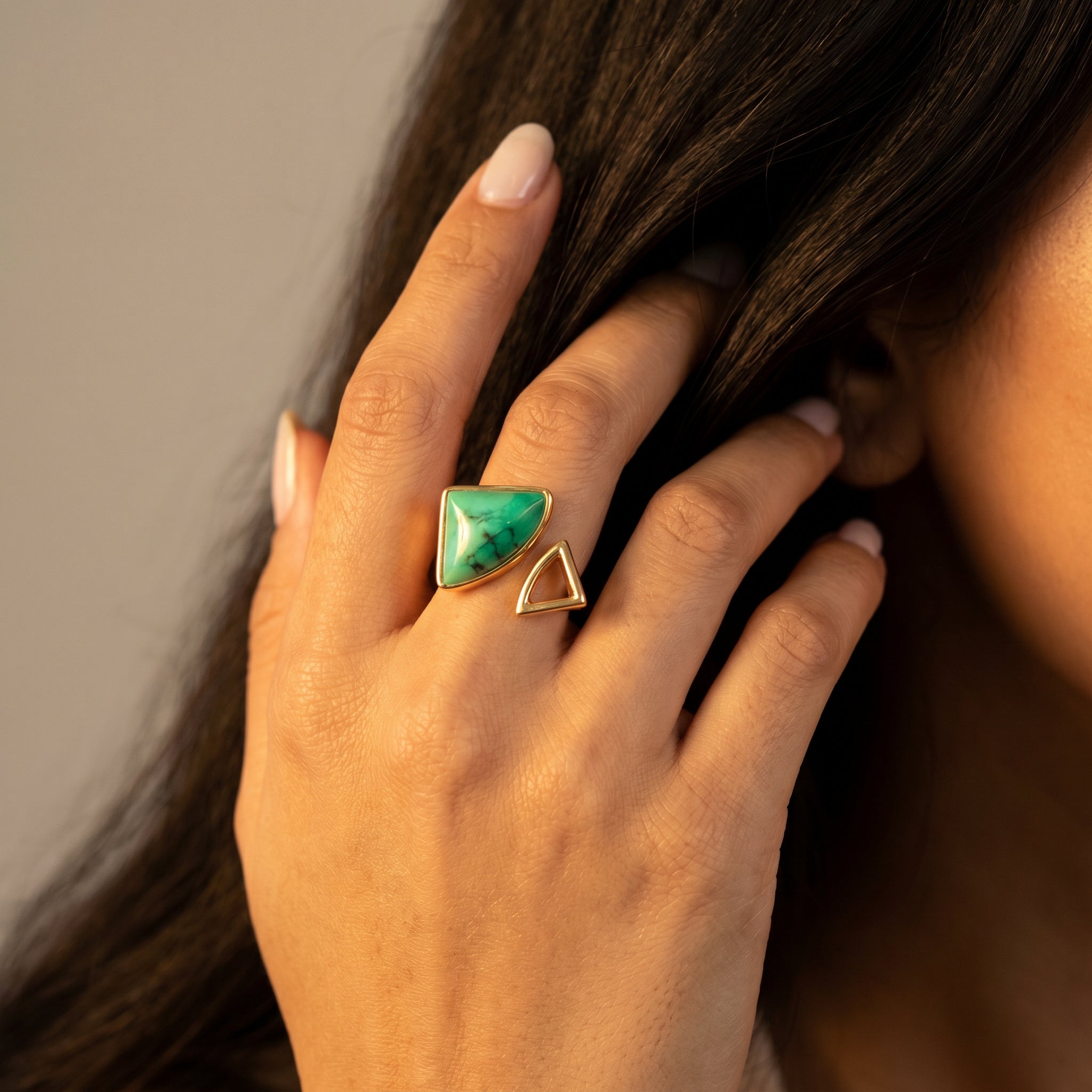 Hand wearing a Purplee Store ELAN Geometric Bypass Ring with a gold band, touching hair against a neutral background
