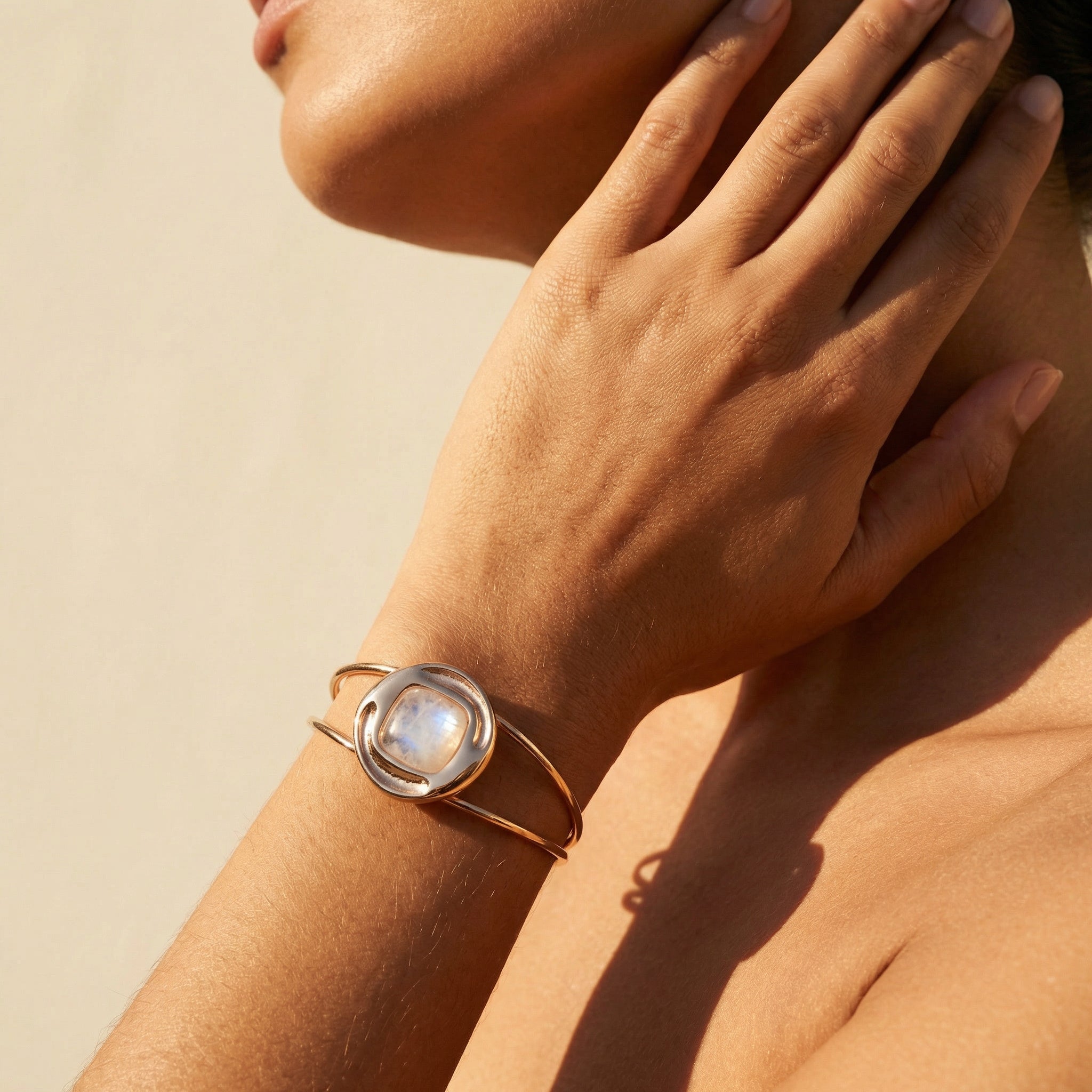 Close-up of a hand wearing a Natural Opal Bracelet 24K Gold Plated - Nautilus Design Handcrafted Jewelry on a beige background. Purplee Store