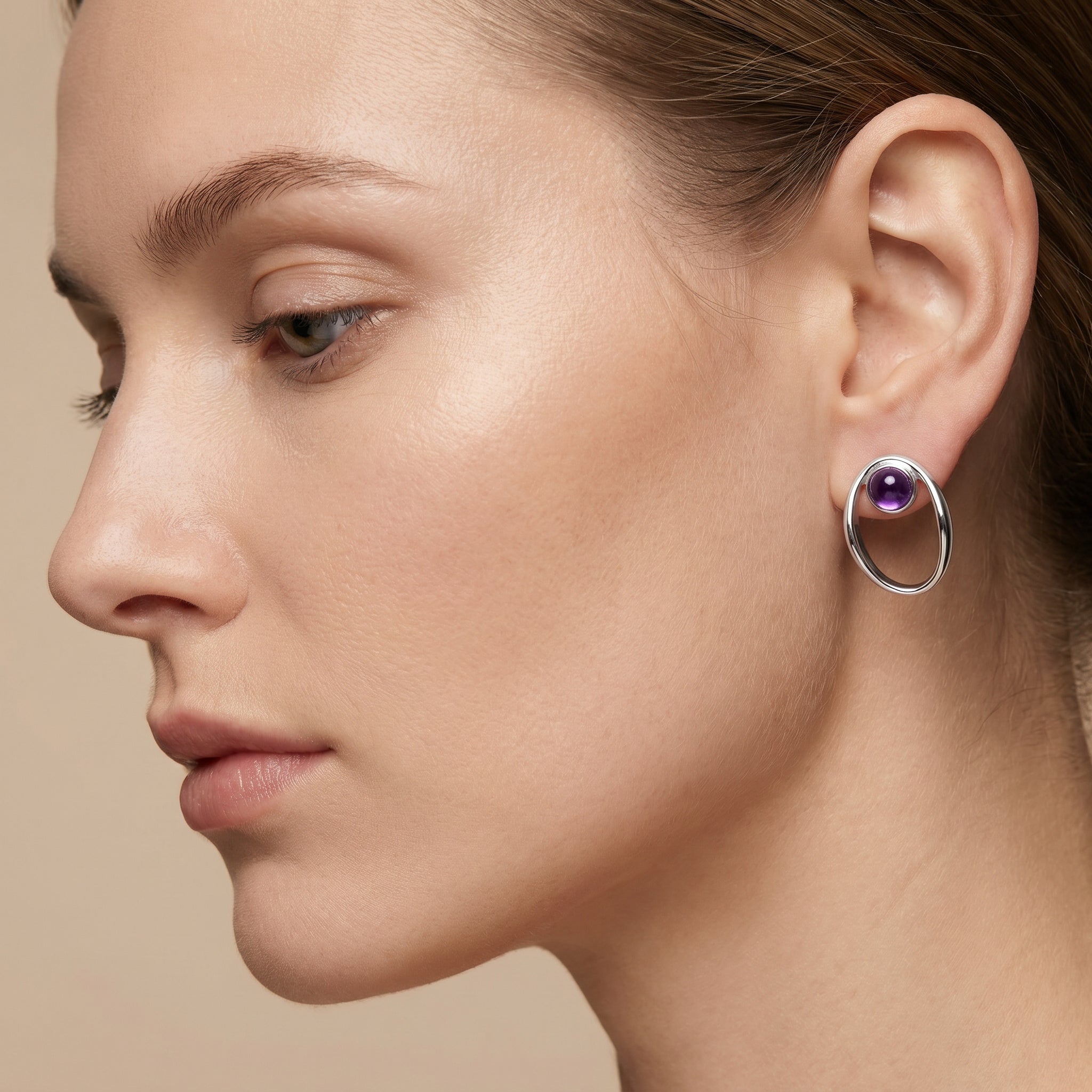 Close-up of a woman wearing a Purplee Store PIORELLE Sculpted Amethyst Earring on a beige background
