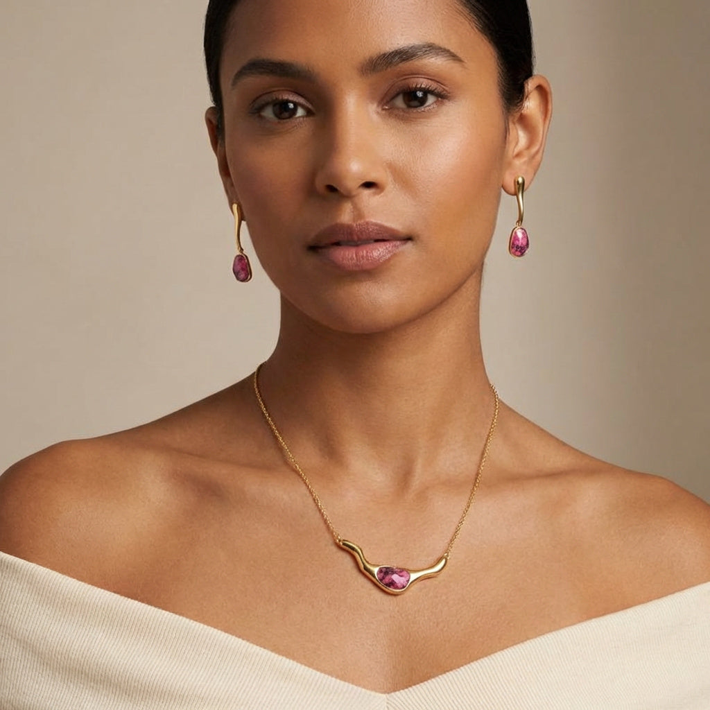 Woman wearing a Rhodonite 24K Triple Gold Plated Statement Necklace and earrings set with a beige background. Purplee Store
