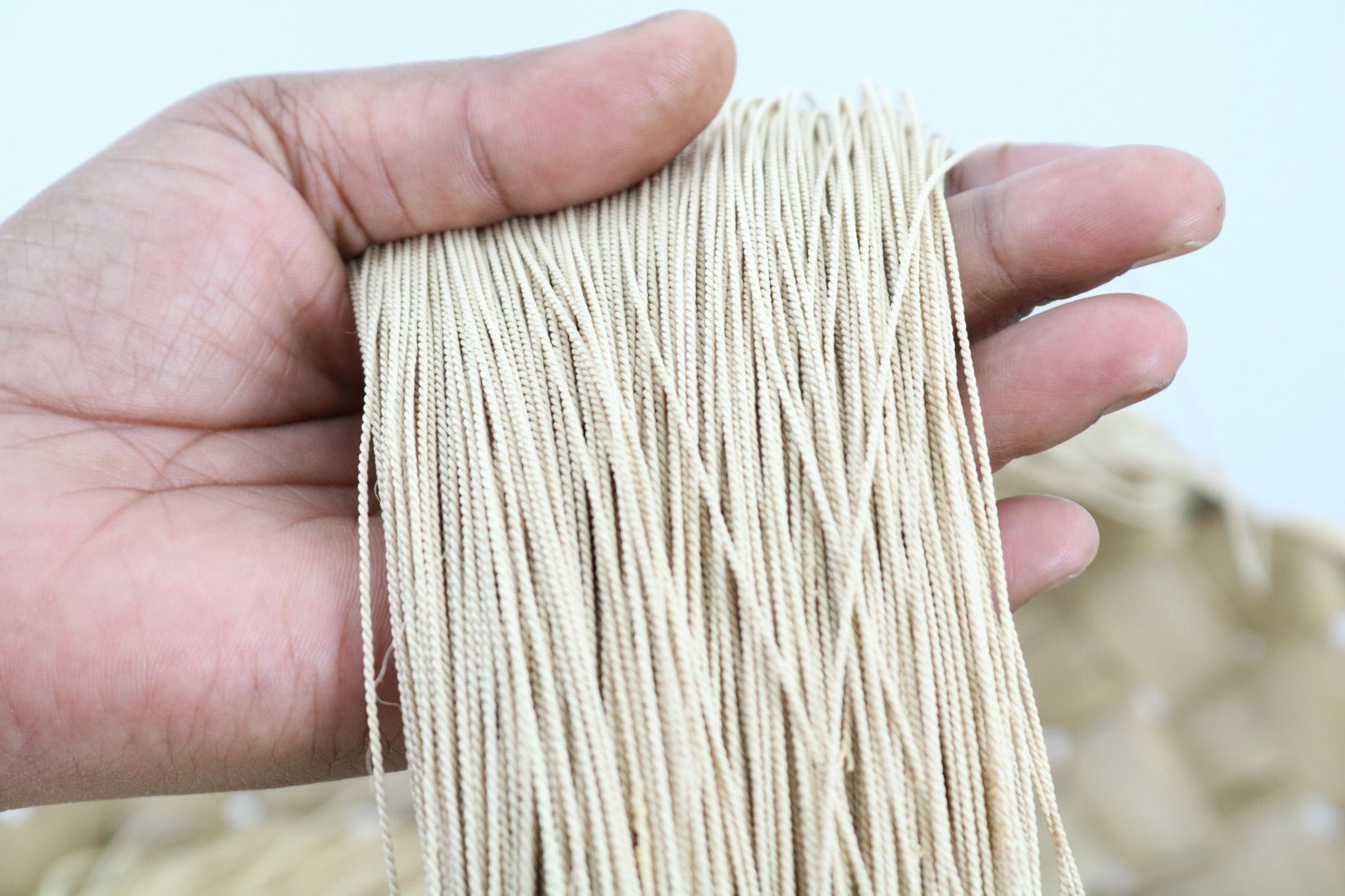 Mano sosteniendo hilos naturales de palha de burití – materia prima sostenible utilizada en joyas artesanales