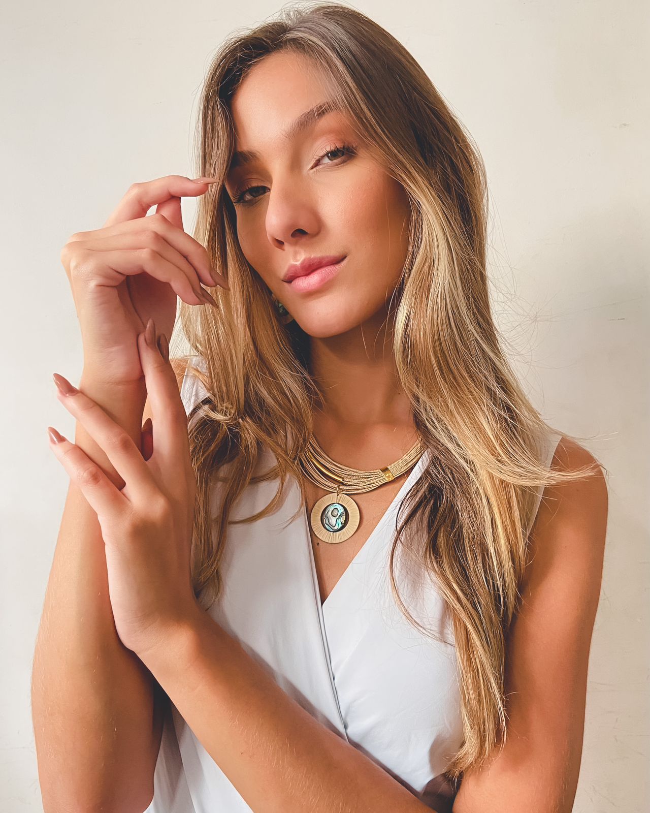 Mujer usando Collar artesanal de Purplêe Store hecho con palha de burití y colgante redondo de abalone natural – joya sostenible elegante con acabado dorado