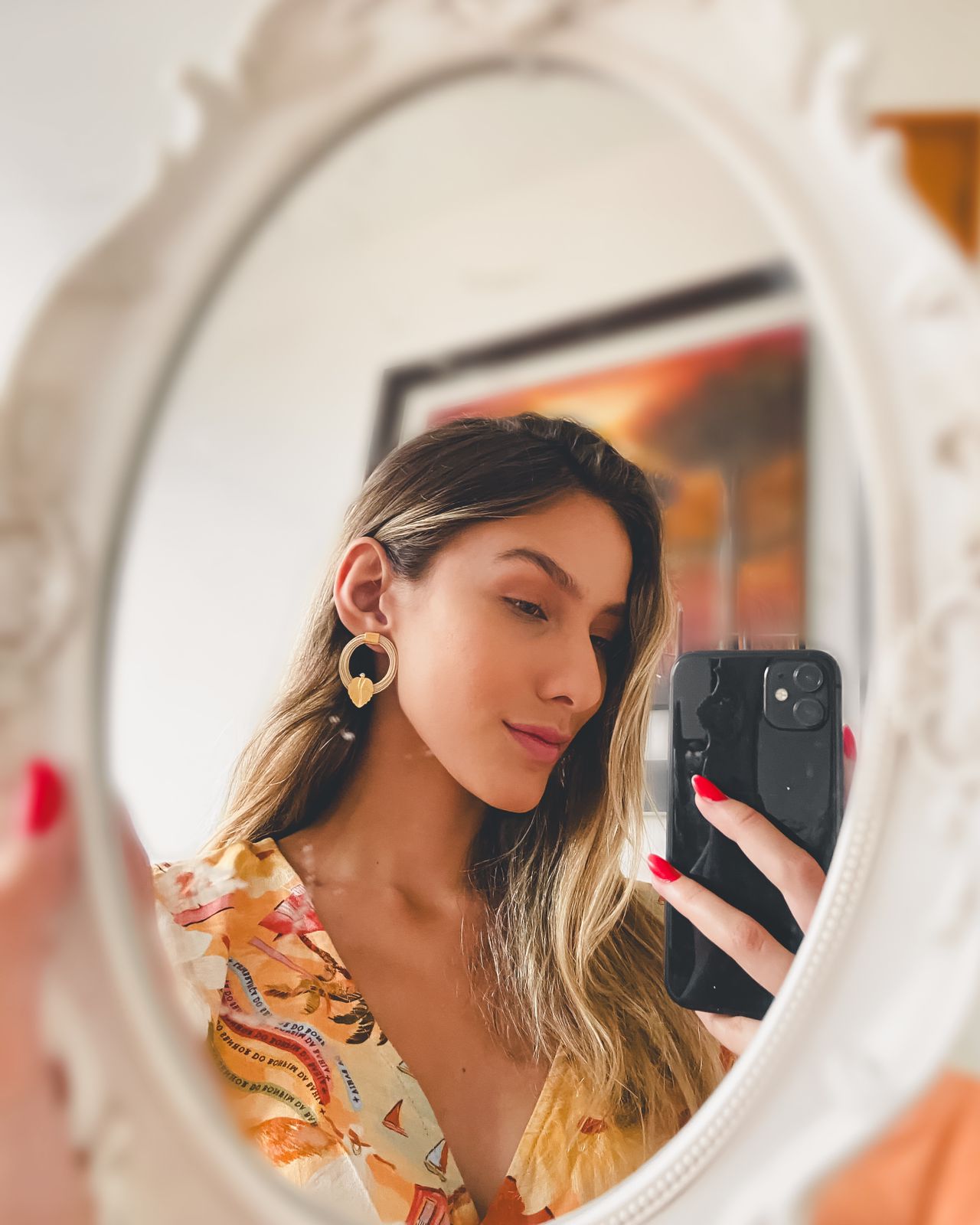 Mujer haciendo selfie usando Pendientes circulares en palha de burití con hoja dorada – joyas sostenibles hechas a mano de Purplêe Store