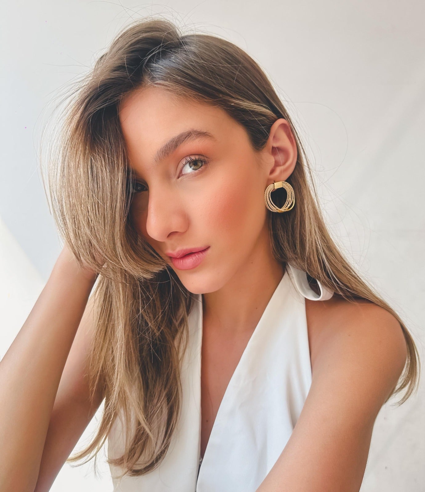 Mujer elegante usando Pendientes circulares de Purplêe Store hechos a mano en palha de burití con detalle metálico dorado – joyas sostenibles y elegantes