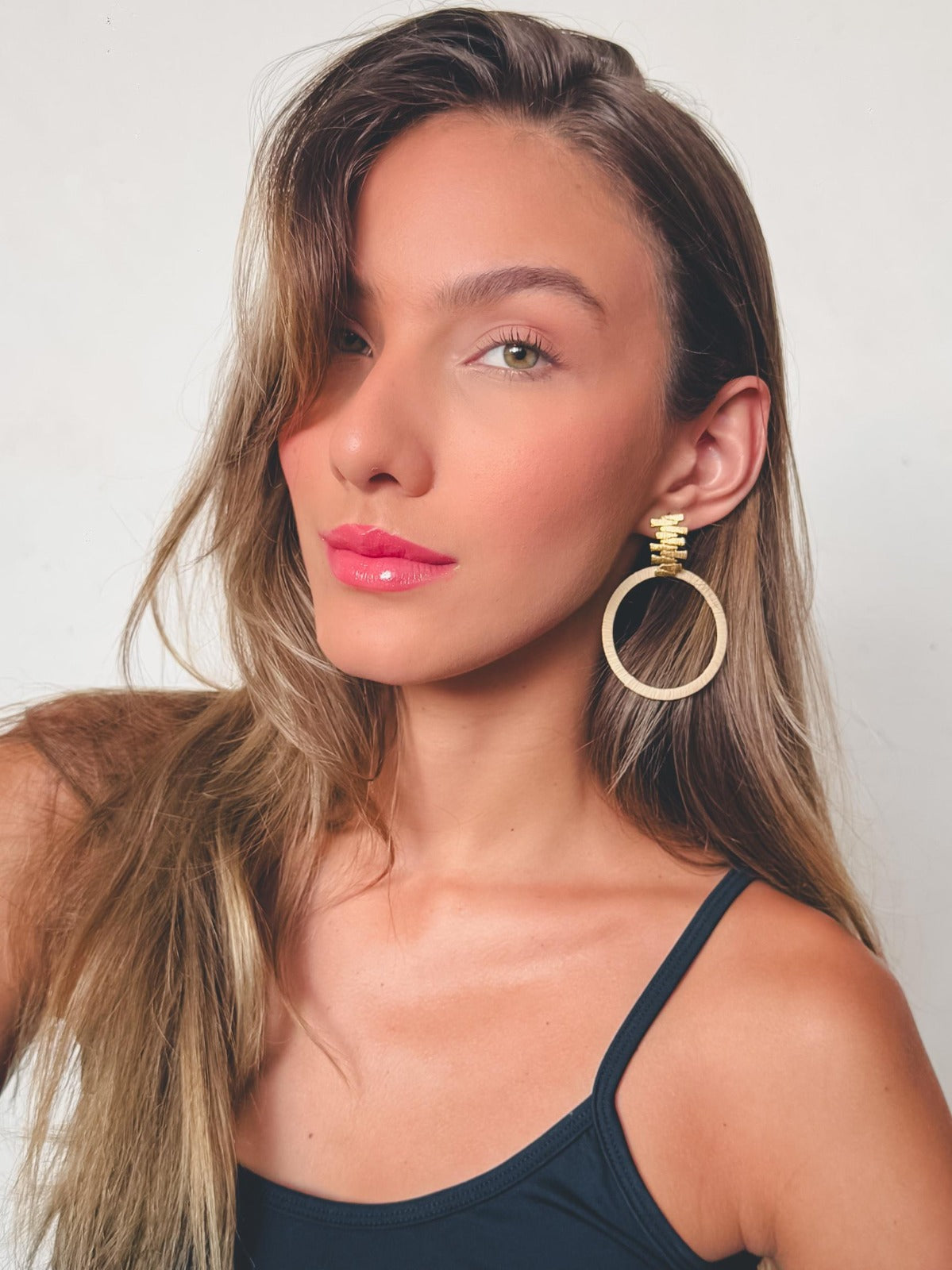 Mujer usando Pendientes circulares de Purplêe Store hechos a mano en fibras naturales con pieza dorada texturizada – joyas sostenibles de diseño exclusivo