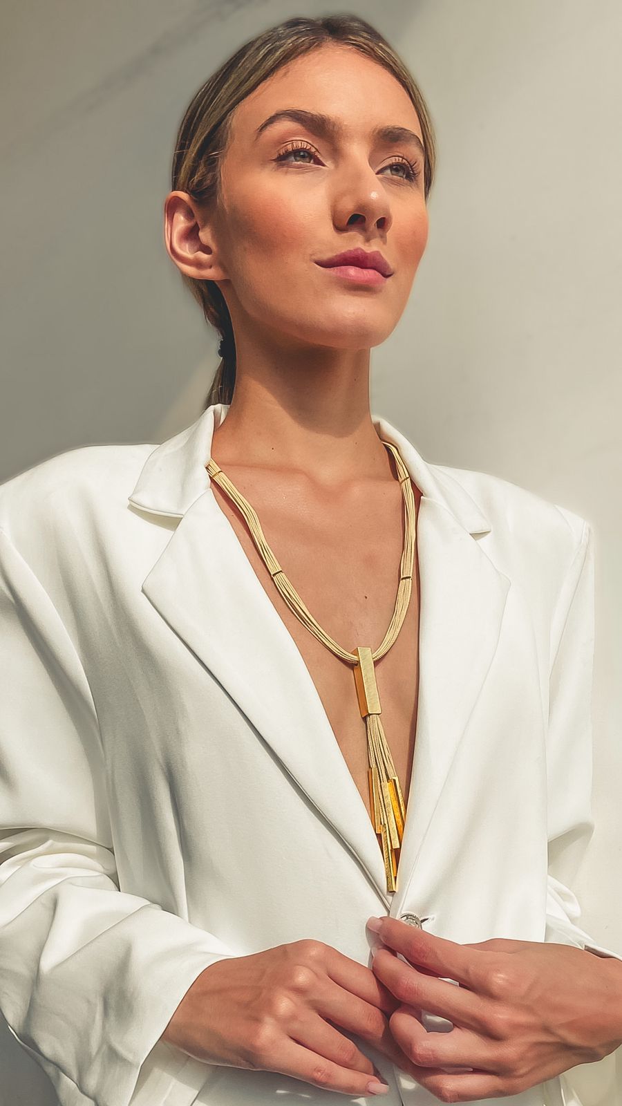 Mujer elegante usando Collar largo de Purplêe Store hecho a mano en palha de burití con colgante de flecos dorados – joya sostenible con movimiento y estilo elegante