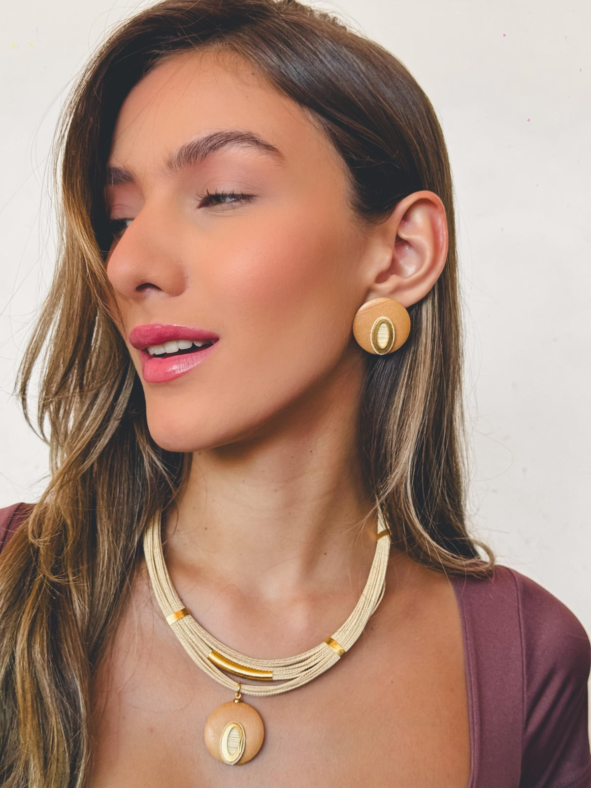 Mujer feliz usando Conjunto artesanal de Purplêe Store con collar y pendientes hechos a mano en palha de burití y fibras naturales – joyas sostenibles con diseño simbólico y empoderador