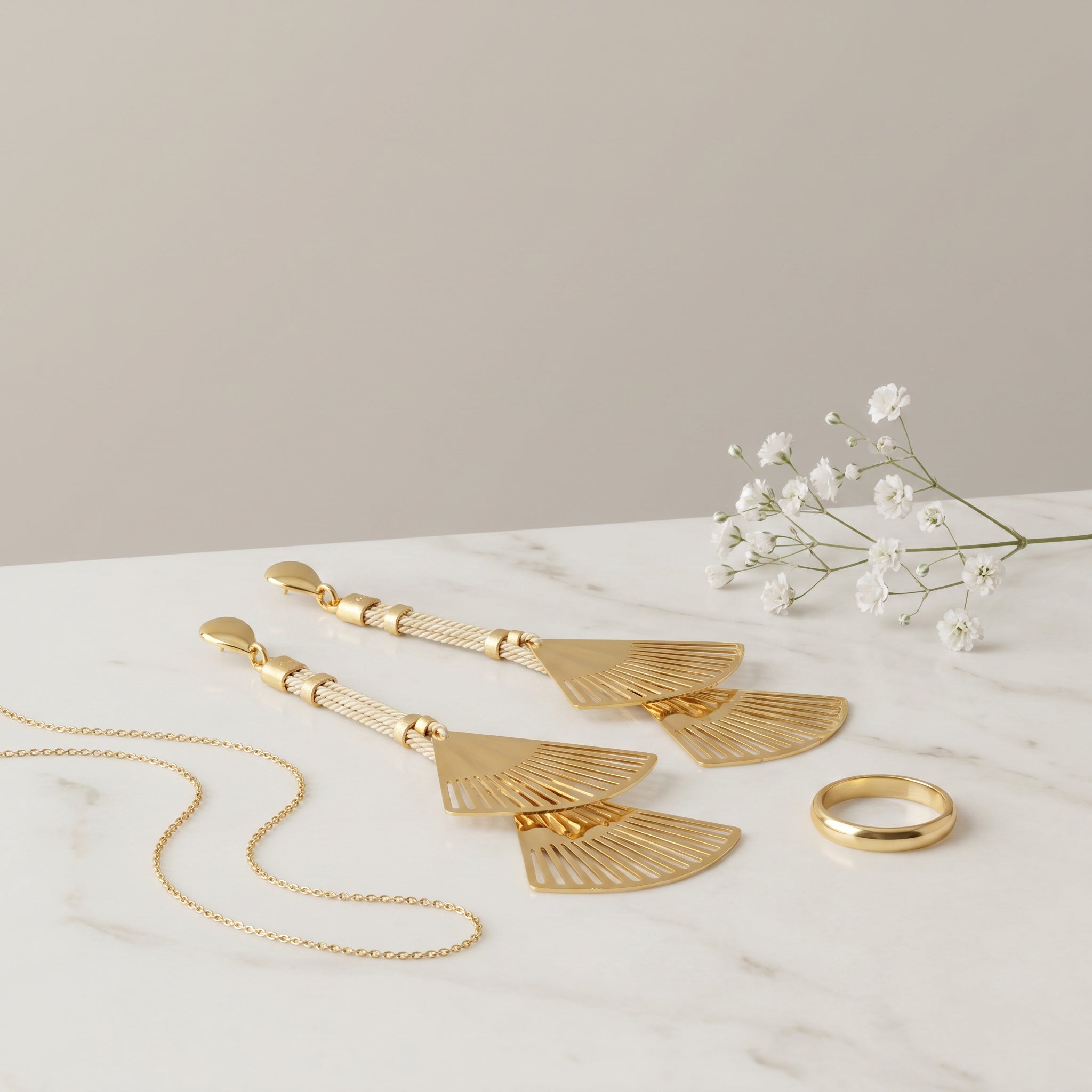 Purplee Store Buriti Artisanal Isolde Earrings with fan-shaped pendants and a ring on a marble surface with white flowers.