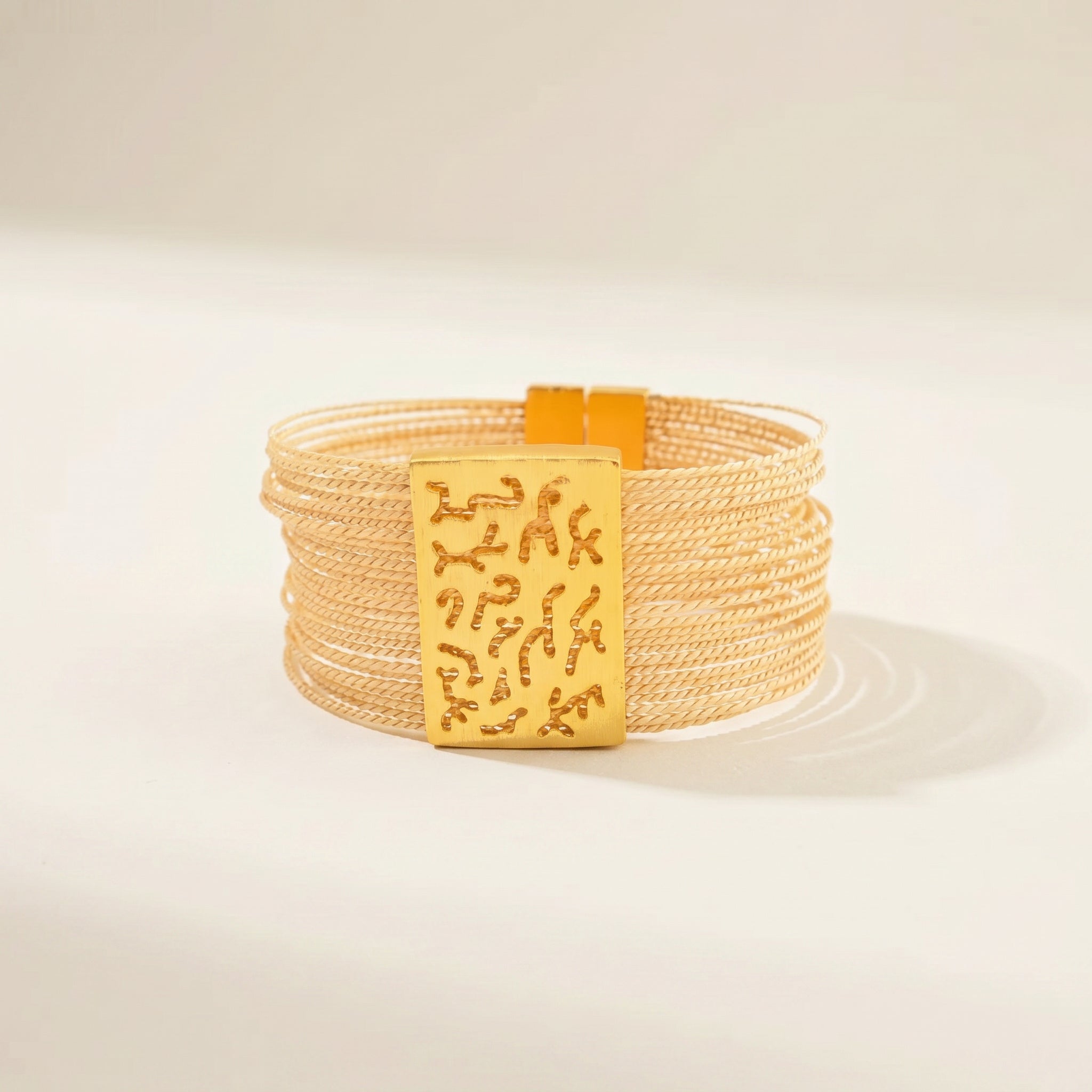 Beige bracelet with a gold tag featuring Chinese characters on a beige background. Purplee Store