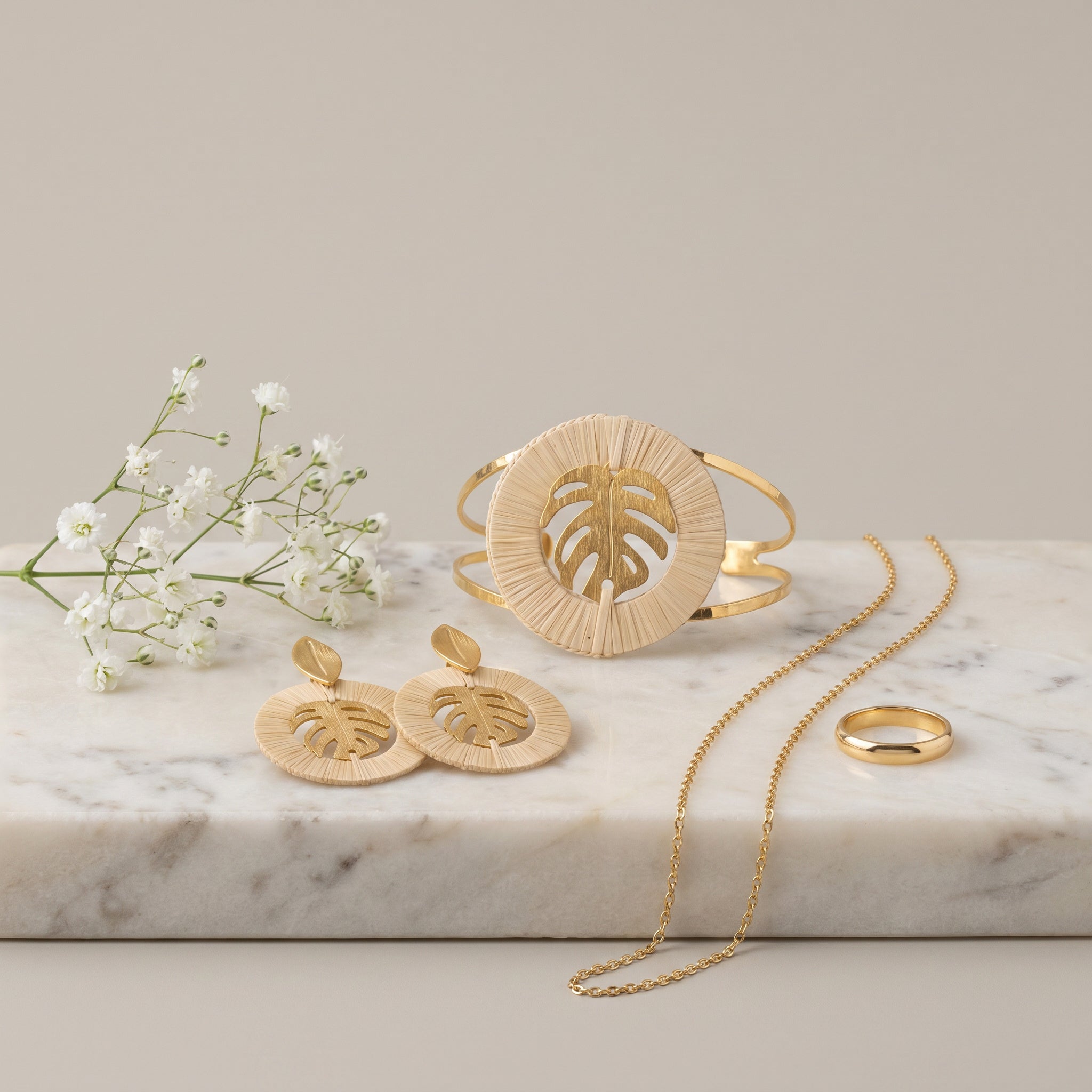 Purplee Store Buriti Artisanal Sorelia Set including earrings, a bracelet, and a ring on a marble surface with small white flowers.