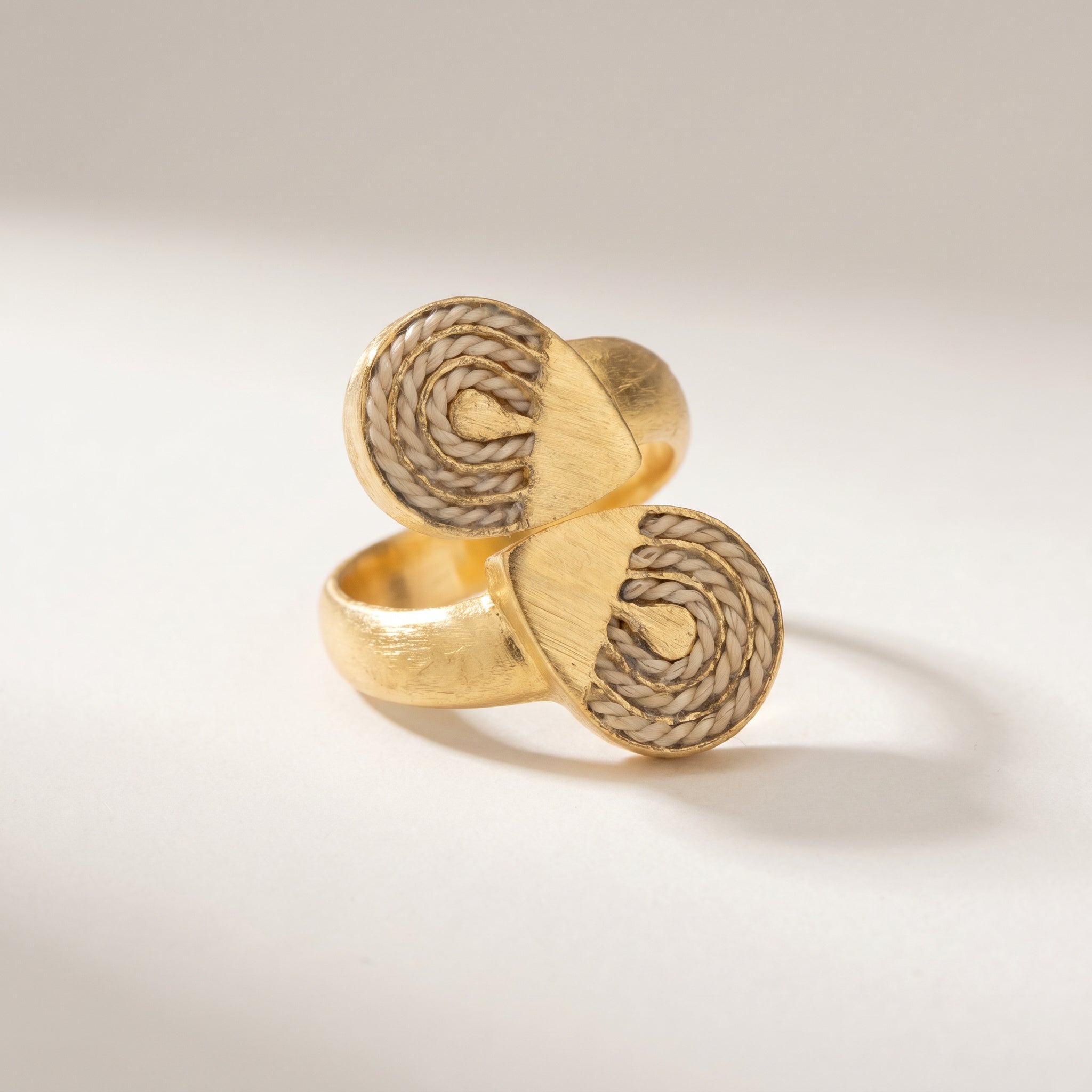 Pair of gold spiral-patterned earrings on a light background.Purplee Store