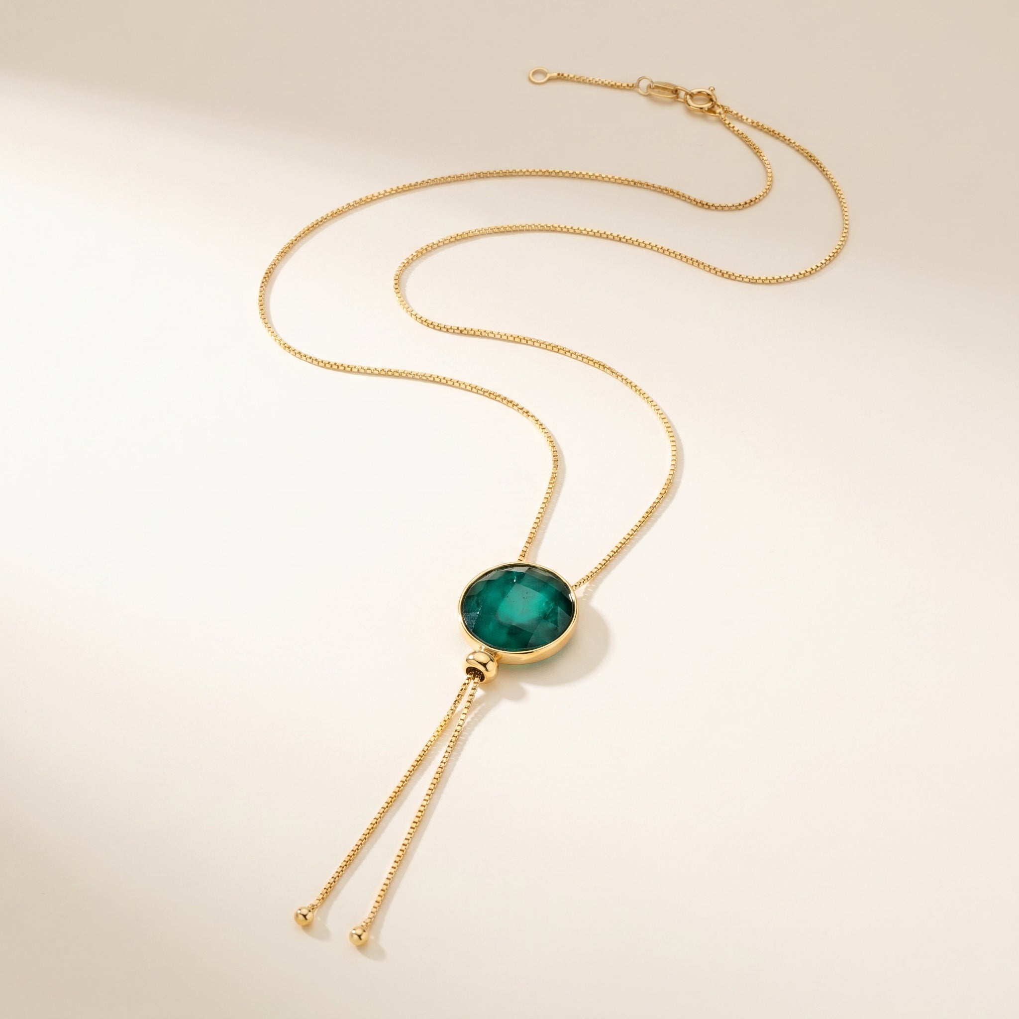 Purplee Store ELAN Emerald Statement Necklace  pendant on a beige background