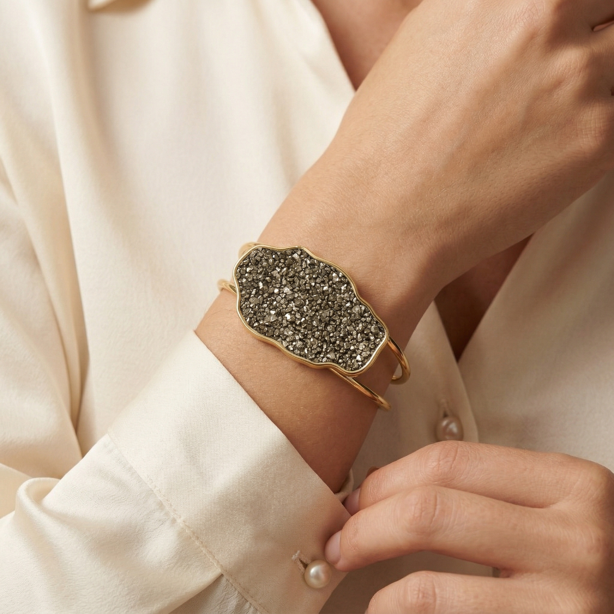 Close-up of a hand wearing Earthly Opulence Golden Fire Pyrite Cuff|Purplee Store on a light-colored shirt.