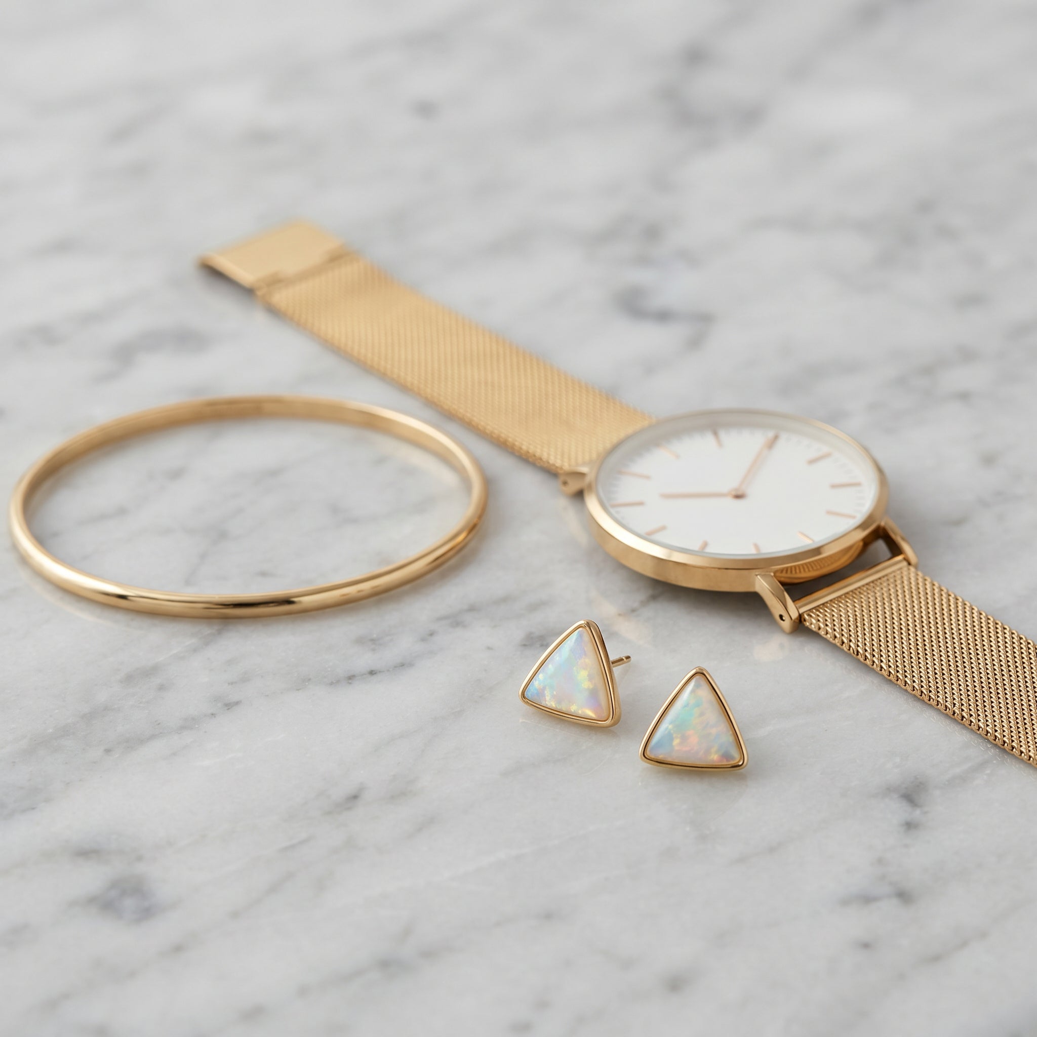 Gold watch, bracelet, and Purplee Store ICON Luxury Triad Opal Earrings  on a marble surface