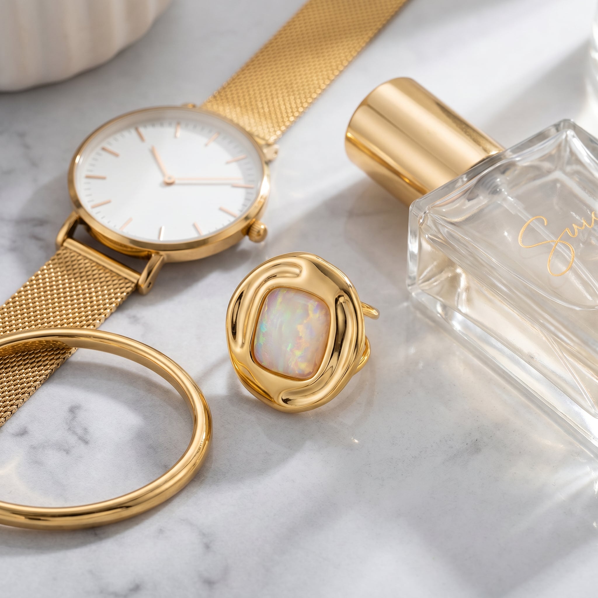Gold watch, Purplee Store ICON Nautilus Opal Premium Ring, and perfume bottle on a marble surface
