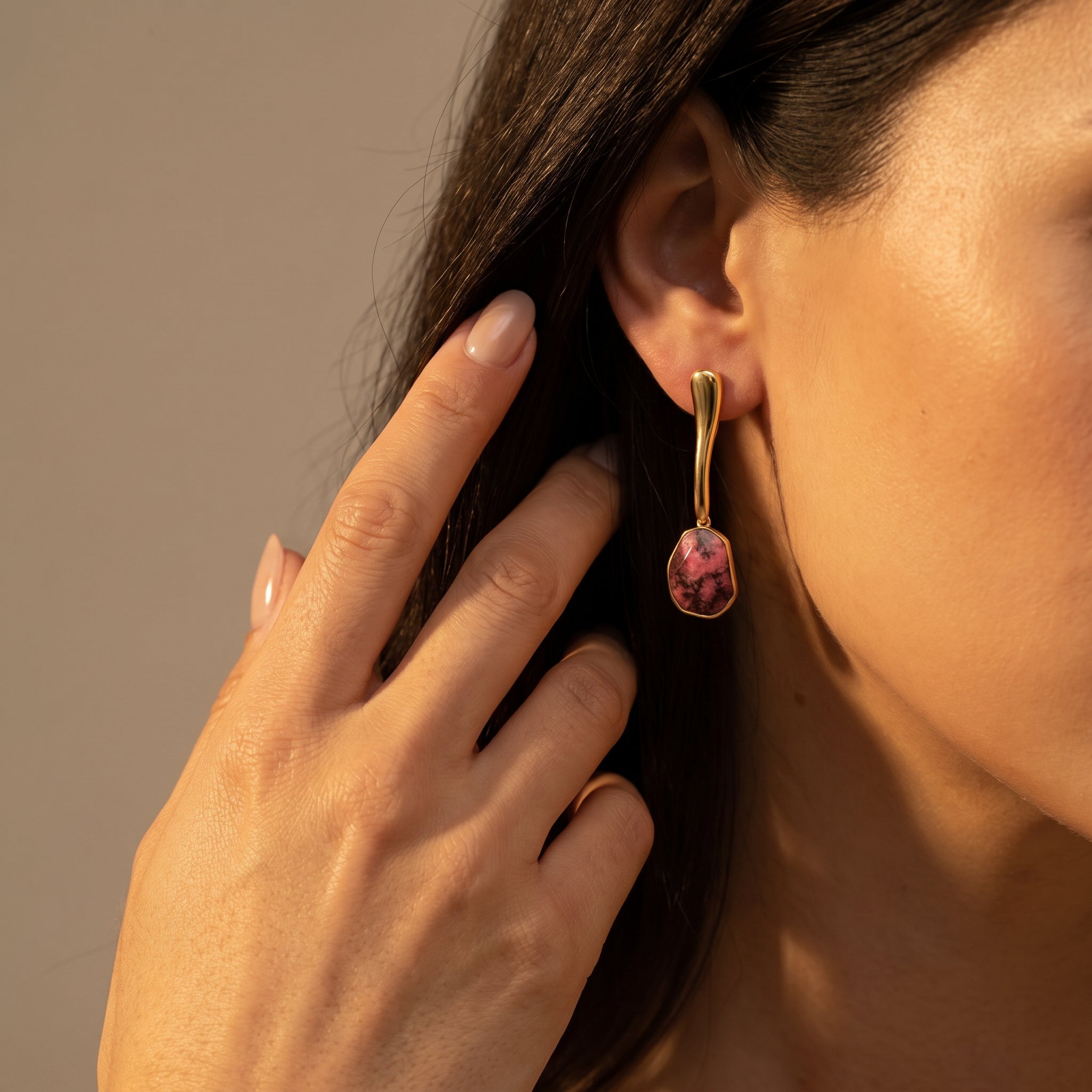 Close-up of a woman wearing a Purplee Store ICON Rhodonite Sculptural Earrings against a neutral background