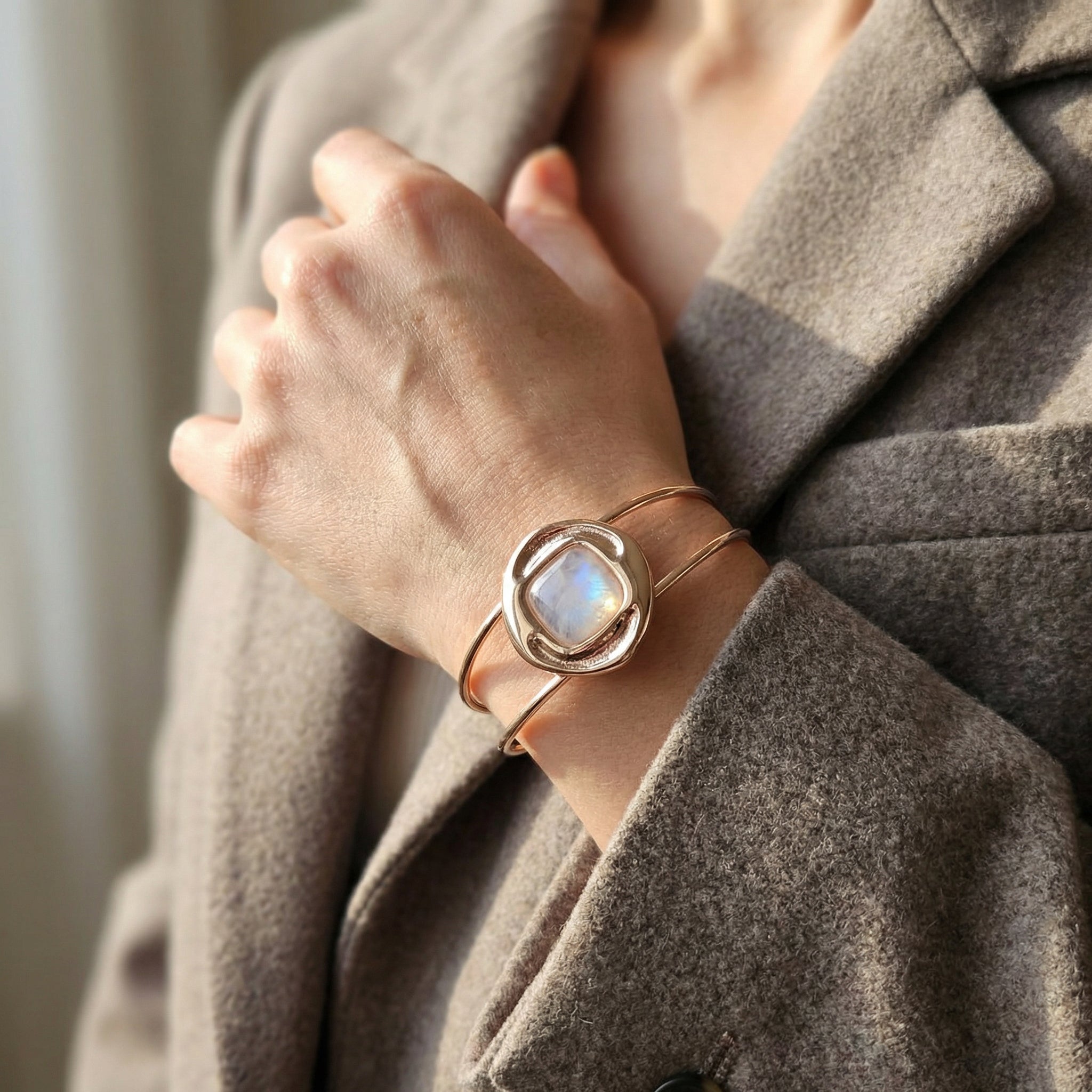 Woman wearing a Natural Opal Bracelet 24K Gold Plated - Nautilus Design Handcrafted Jewelry, wrapped in a gray coat. Purplee Store