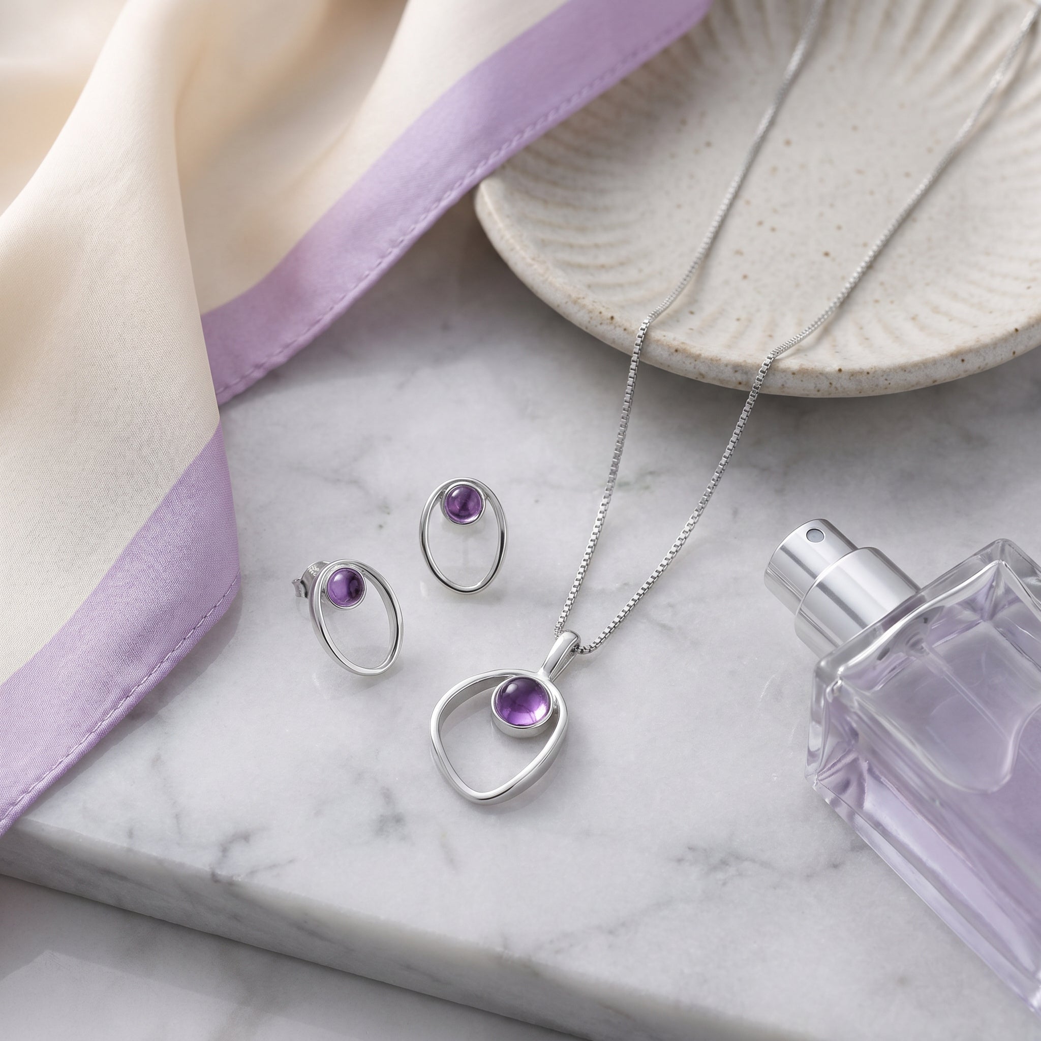 Purplee Store PIORELLE jewellery  set on a marble surface with a lavender fabric and white dish.