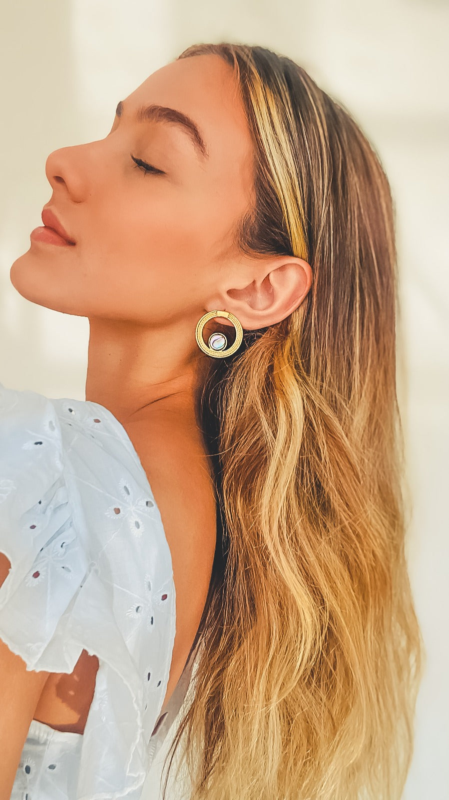 Mujer usando Pendientes circulares de Purplêe Store hechos a mano en palha de burití con piedra abalone natural – joyas sostenibles y exclusivas