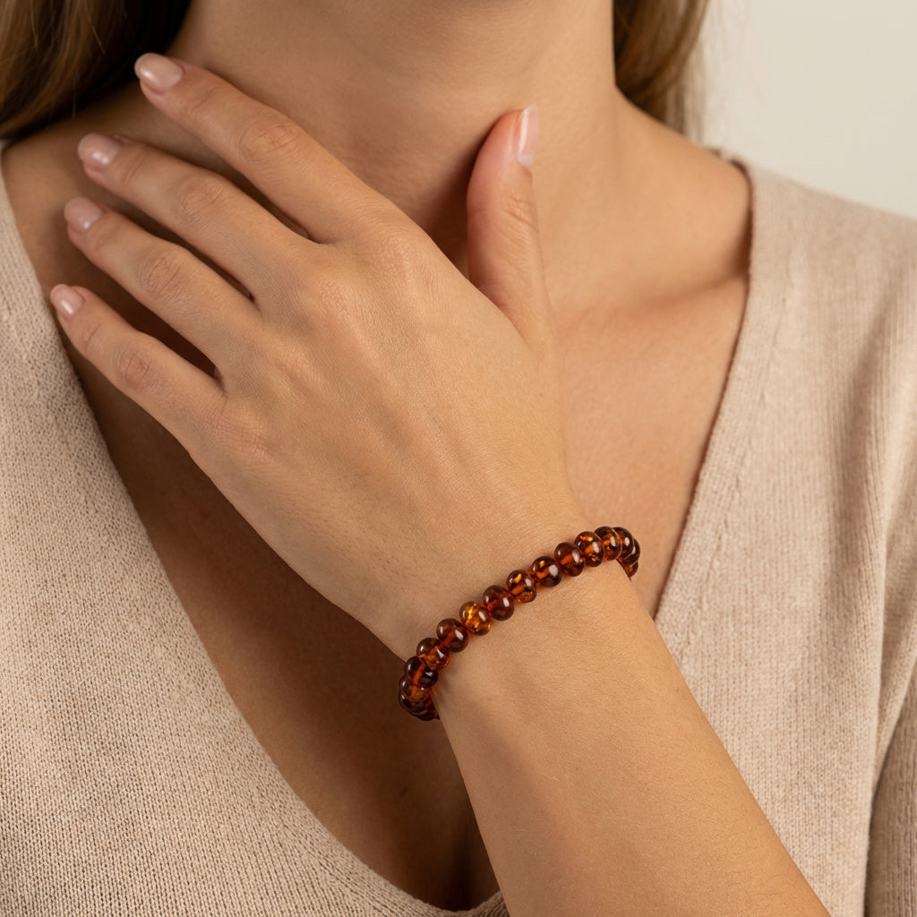 Close-up of a hand wearing a Amber Cognac Energy Olive Bracelet|Purplee Store on a neutral background