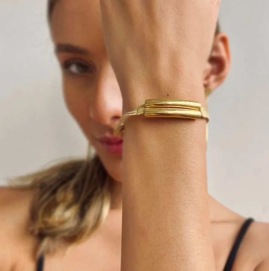 Mujer usando Pulsera artesanal en palha de burití con detalles dorados – joya sostenible hecha a mano con diseño elegante. Purplee Store